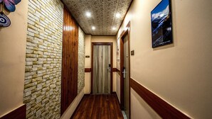 A hallway with a brick wall, wooden paneling, and a ceiling with a leaf pattern. - Hotel Ambrosia (Gangtok)