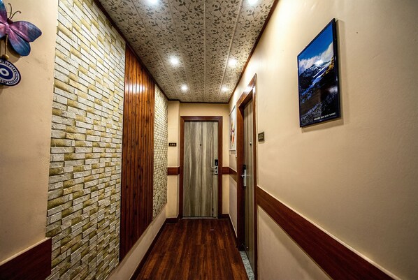 Un couloir avec un mur en briques, un lambris en bois et un plafond orné d’un motif de feuilles.