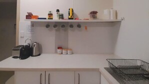 Een keuken met een wit aanrecht, een koffiezetapparaat, een broodrooster en een spoelbak.