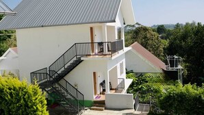 A two-story building with a metal roof, a staircase leading to the upper floor, and a balcony. - Hazeberg Resort Munnar (Devikolam)