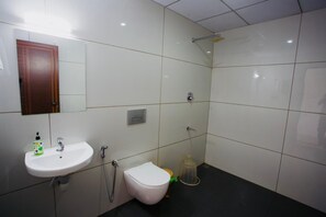 A bathroom with a white sink, mirror, and toilet. - Hazeberg Resort Munnar (Devikolam)