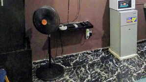 A room with a television mounted on the wall, a standing fan, a microwave, and a refrigerator. - Short Let in lagos business school Ajah  (Lekki)