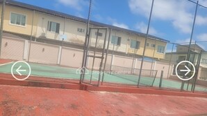 A property center with a fenced tennis court and a building with multiple windows. - Short Let in lagos business school Ajah  (Lekki)