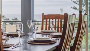 A dining table set with plates, cutlery, and wine glasses, with wooden chairs and a view of the outdoors. - Paradiso Paradise 336 3BRM Oceanfront (Kingscliff)