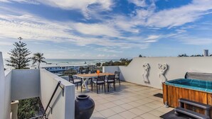 A rooftop terrace with a view of the ocean, a table with chairs, a hot tub, and a large vase. - Paradiso Paradise 336 3BRM Oceanfront (Kingscliff)