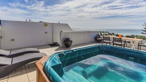 A rooftop terrace with a hot tub, lounge chairs, and a table with chairs. - Paradiso Paradise 336 3BRM Oceanfront (Kingscliff)