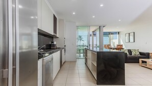 A modern kitchen with a central island, a dining area with a view, and a living space with a sofa and a coffee table. - Paradiso Paradise 336 3BRM Oceanfront (Kingscliff)