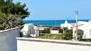 Et kystnære boligområde med hvide huse, frit kig til havet og en belagt sti.