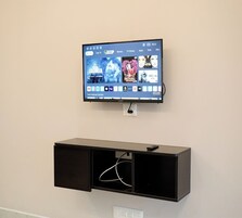 Un televisor de pantalla plana montado en la pared con un mueble de entretenimiento negro debajo.