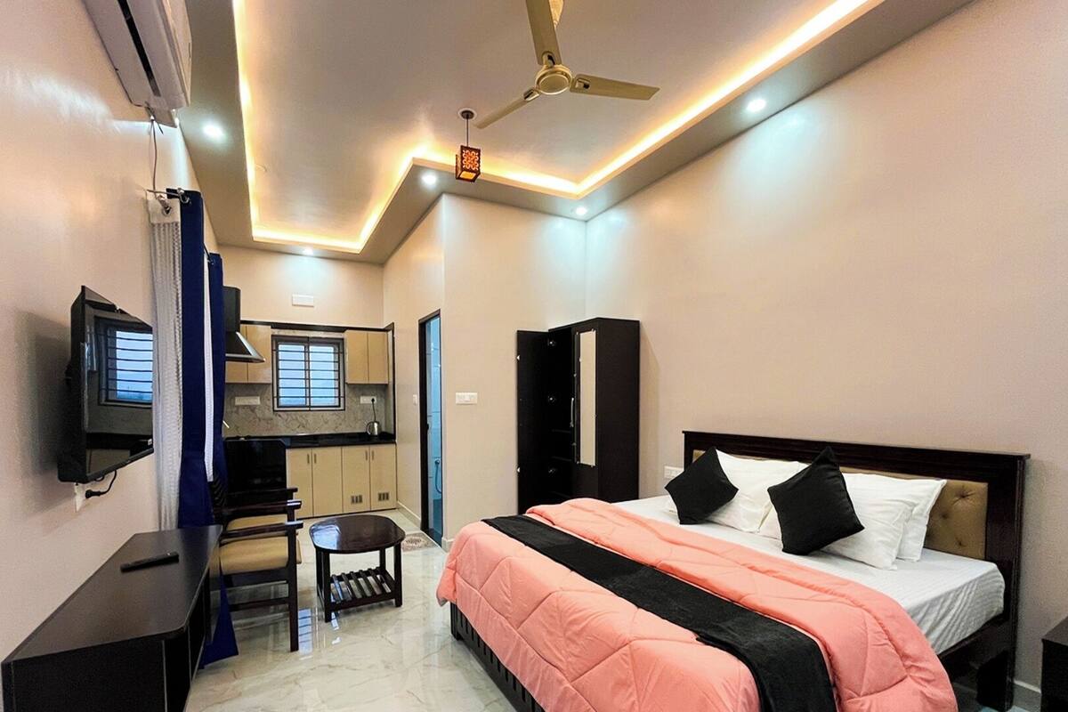 A modern bedroom with a bed, bedside tables, a desk, and a television.