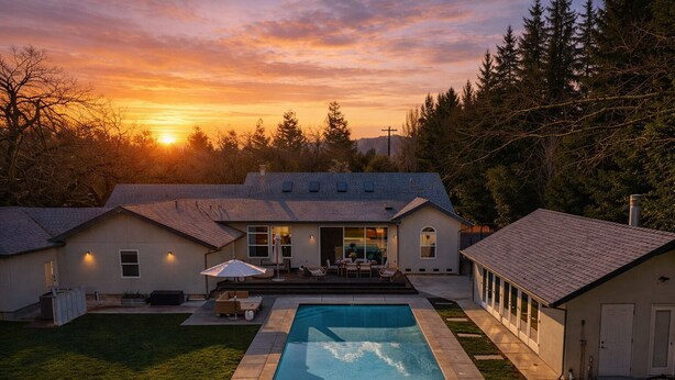 Una casa moderna con piscina, un patio con mobiliario exterior y un garaje.