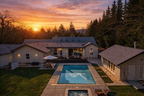 Ein modernes Haus mit Swimmingpool, Terrasse und Gartenmöbeln sowie einer Garage.