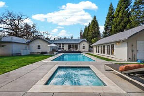 Une maison moderne dotée d’une piscine, d’un patio couvert et d’une pelouse bien entretenue.