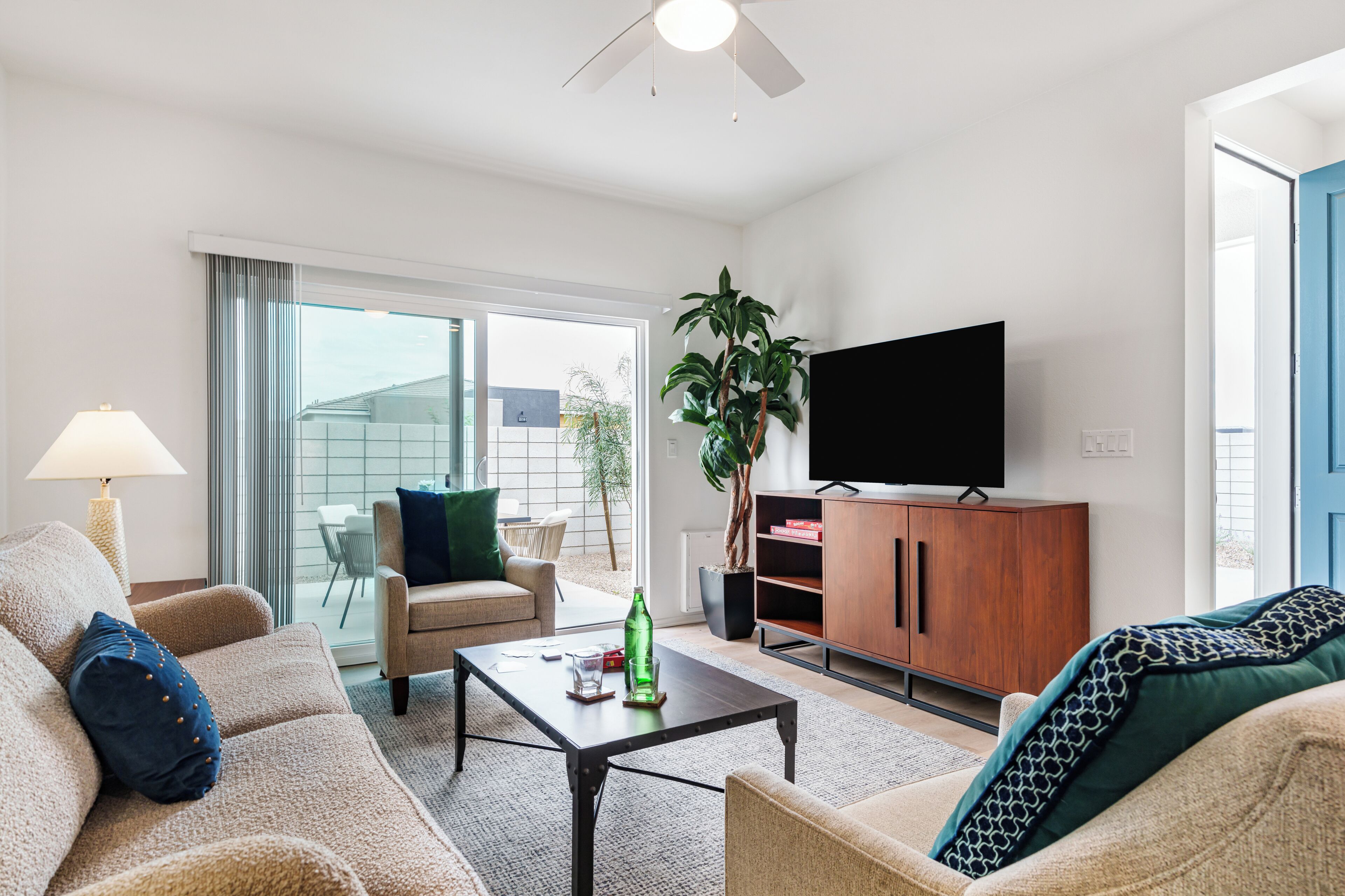A living room with a sofa, armchair, coffee table, TV, and a plant.