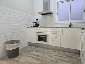 Eine kompakte Küche mit weißen Schränken, einem eingebauten Backofen und einem Fenster über der Spüle.