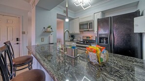 Una cucina con piani di lavoro in granito, elettrodomestici in acciaio inossidabile e forno a microonde integrato.
