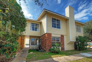 A two-story house with a brick chimney, a front porch, and a small front yard. - Coastal Condo + Near Oso Bay & Padre Beaches | Seaside Haven (Corpus Christi)
