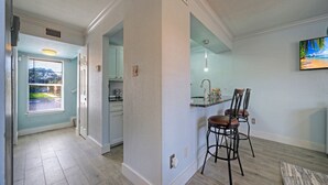Una cucina con un angolo bar, una finestra con persiane e vista su una casa.