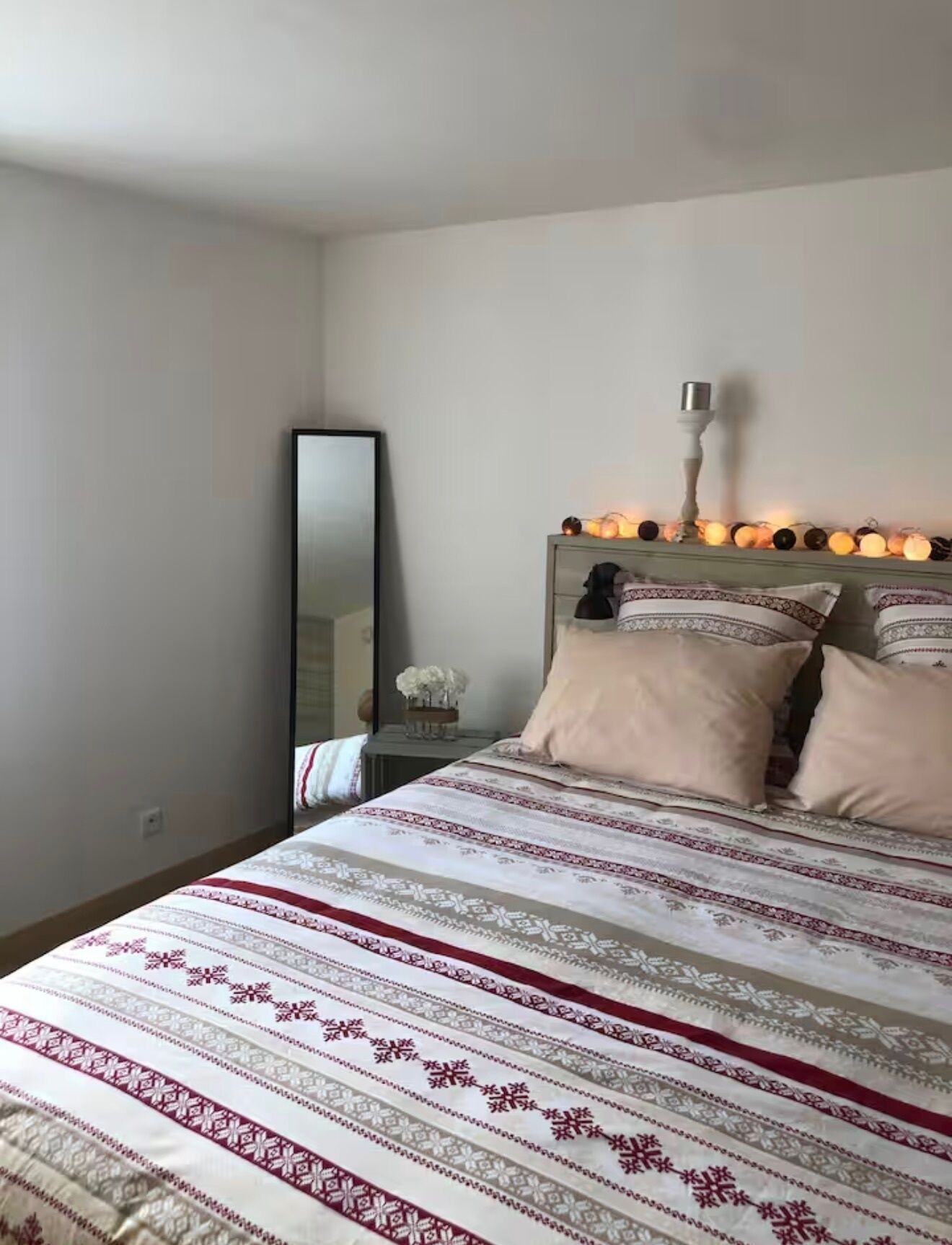 Una camera da letto con un letto, un comodino, uno specchio e una lampada a parete.