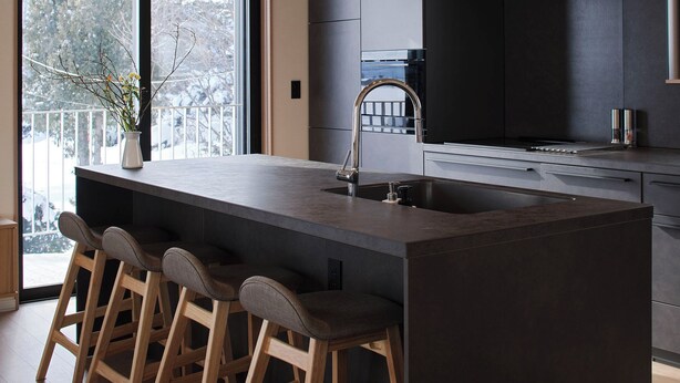 A modern kitchen with a large island, bar stools, and pendant lighting. - Villa Matsu by H2 Life (Nakafurano)