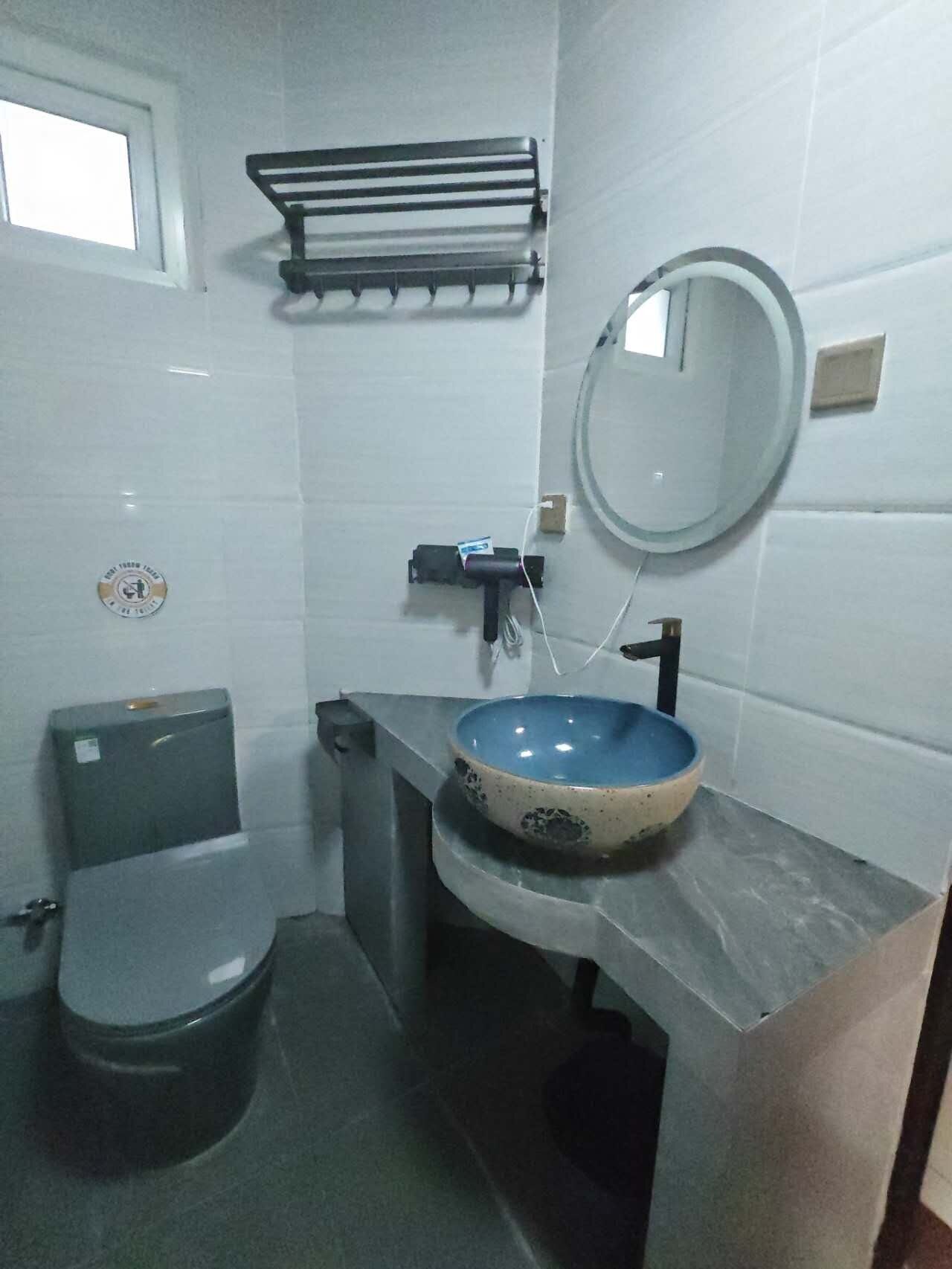 A bathroom with a toilet, sink with a mirror, and a towel rack.