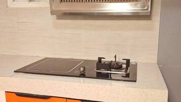 A kitchen with a built-in stove, a window above the sink, and orange cabinets.