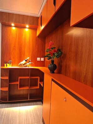 A wooden reception desk with a vase of flowers, a toy car, and a shelf.