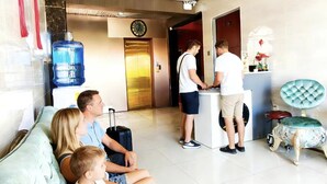 A hotel lobby with a seating area, a reception desk, and a water dispenser. - baoly clark residence (Angeles City)