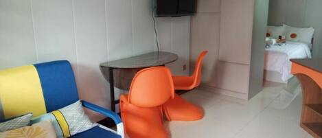 A room with a sofa, a small table, and a bed.
