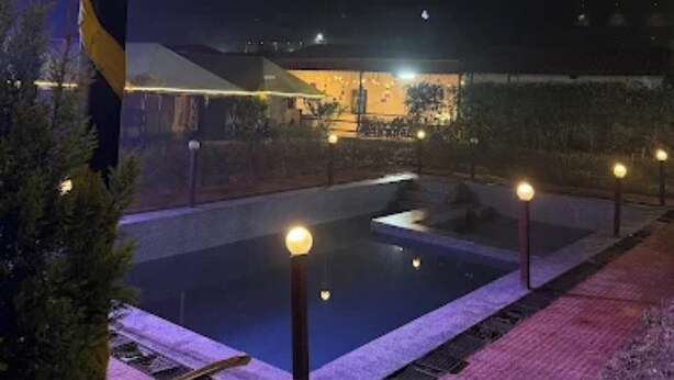 A nighttime pool area with a lamp post and lights along the edge. - Down Valley Resort (Rishikesh)