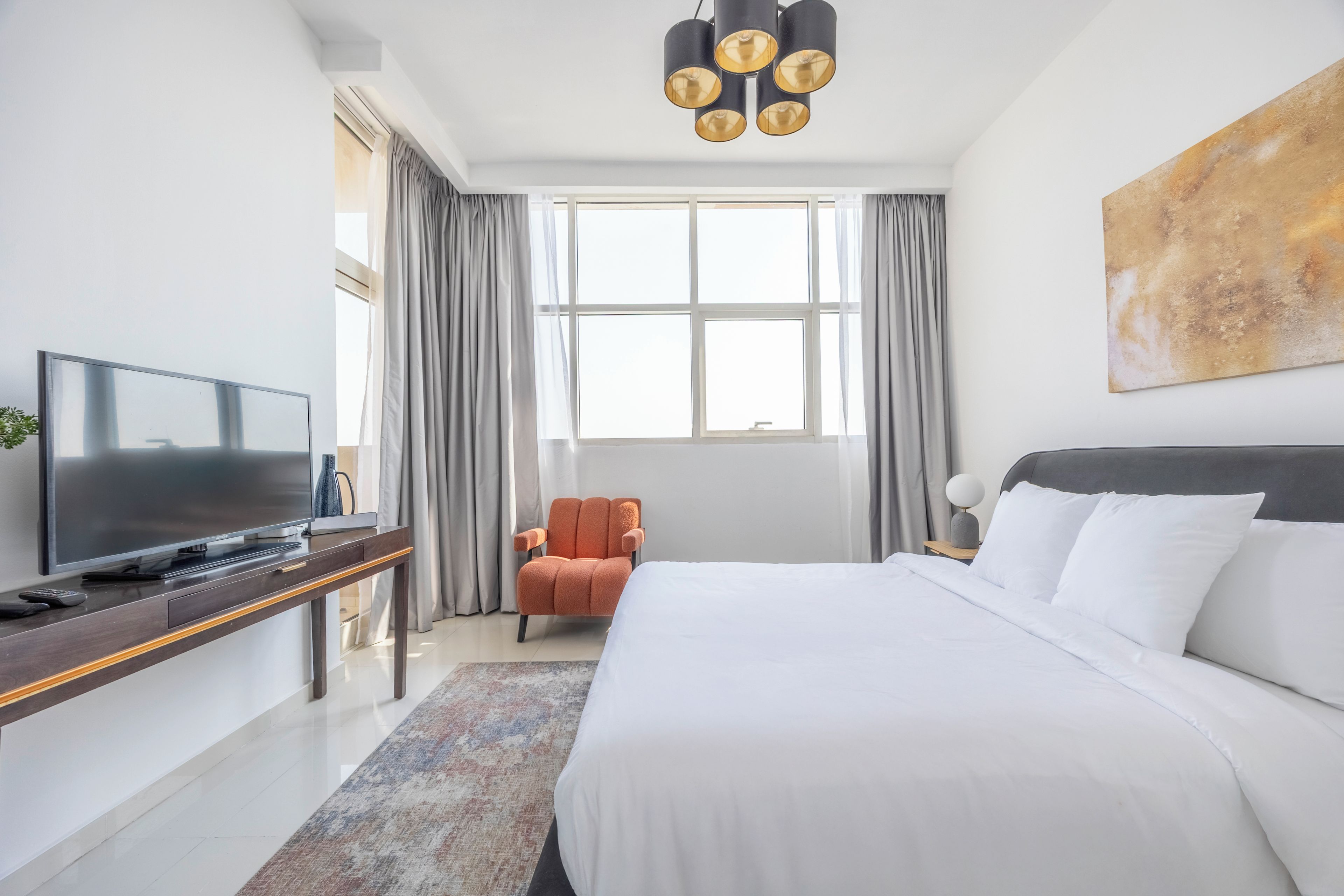 Ein Hotelzimmer mit Bett, Fernseher, Sessel und großem Fenster.