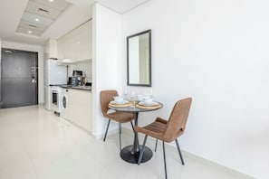 Eine moderne Küche mit Essbereich, inklusive eines runden Tisches mit Stühlen, einer Kaffeemaschine und einem Kühlschrank.