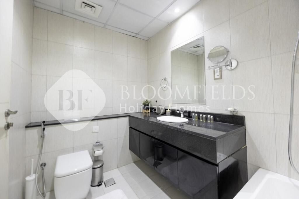 A modern bathroom with a black vanity, a large mirror, and a white toilet.