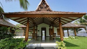 A traditional building with a tiled roof and a covered porch with wooden pillars. - Miraaya Sundara Island Villa (Kuttanad Taluk)