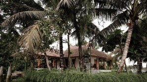 A house with a tiled roof, surrounded by palm trees and a water body. - Miraaya Sundara Island Villa (Kuttanad Taluk)