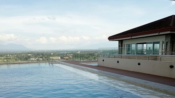 Una piscina infinita con vistas despejadas al paisaje urbano y montañas al fondo.