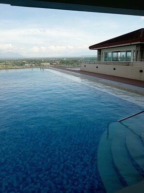 An infinity pool with a clear view of the cityscape and mountains in the background.