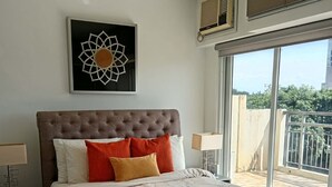 Un dormitorio con una cama grande, una obra de arte en la pared y vistas al exterior.