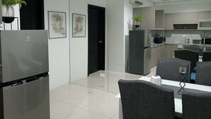 Cocina moderna con refrigerador, microondas y comedor con sillas y mesa.