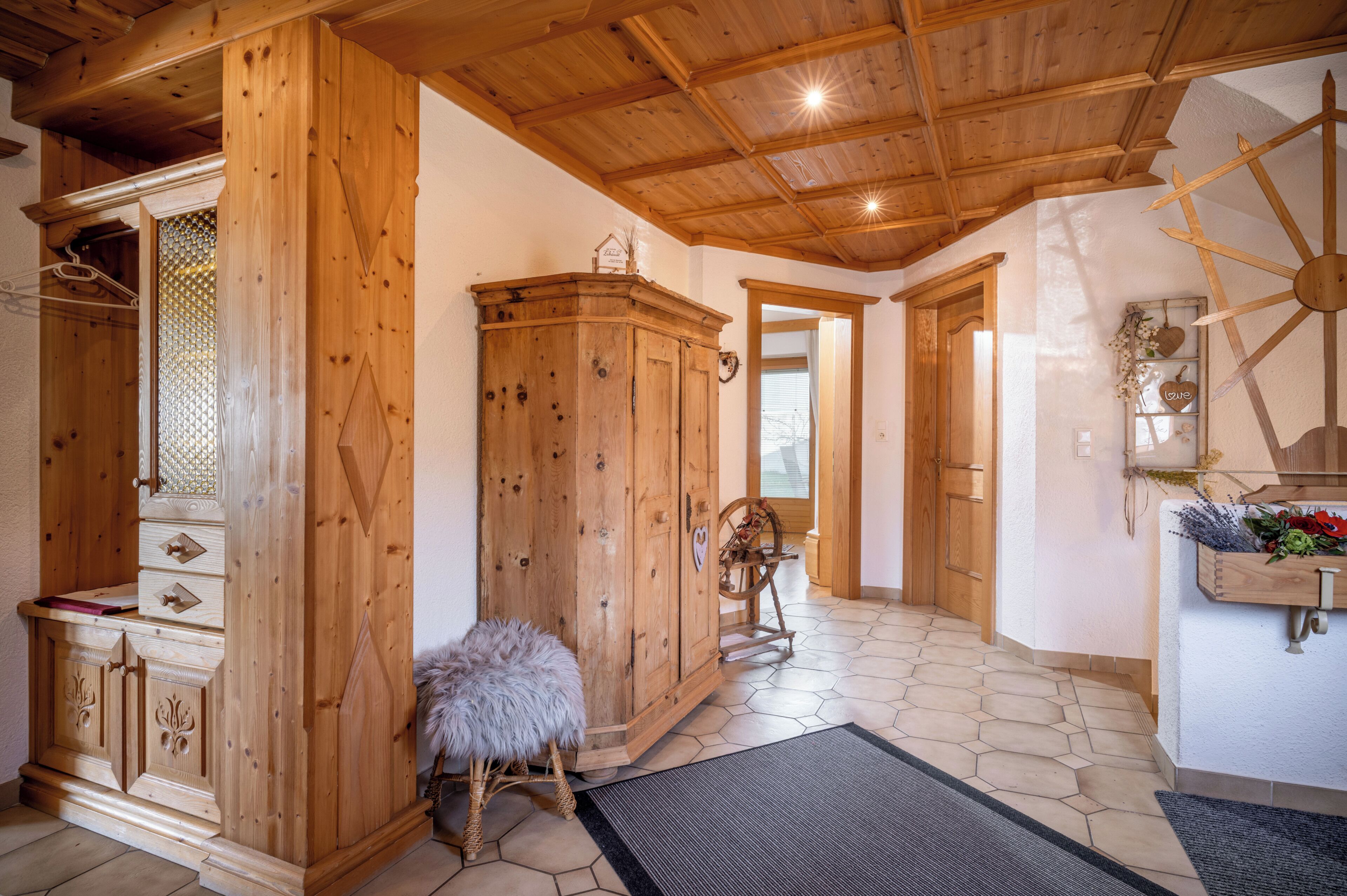 Ein Holzinterieur mit einem Schrank, einem mit Fell bezogenen Hocker und einem Wanddekor.