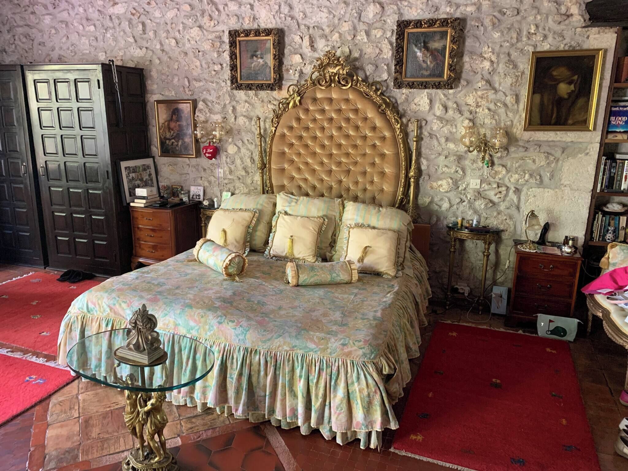 Ein Schlafzimmer mit einem großen Bett, einem Kleiderschrank, einem Schminktisch und einem roten Teppich.