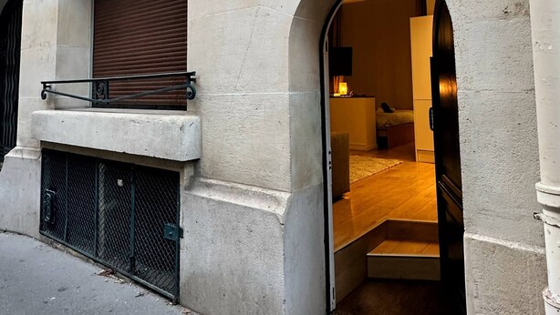 A building facade with arched doorways, a metal balcony, and a sign indicating the architect. - Bright haven between Champs Élysée and Trocadero (Paris)