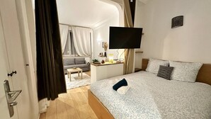 A hotel room with a bed, a desk, a TV, and a view of a balcony. - Bright haven between Champs Élysée and Trocadero (Paris)