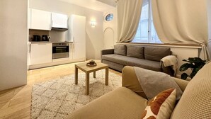 A modern living room with a sofa, a coffee table, and a kitchen area with cabinets and a stove. - Bright haven between Champs Élysée and Trocadero (Paris)