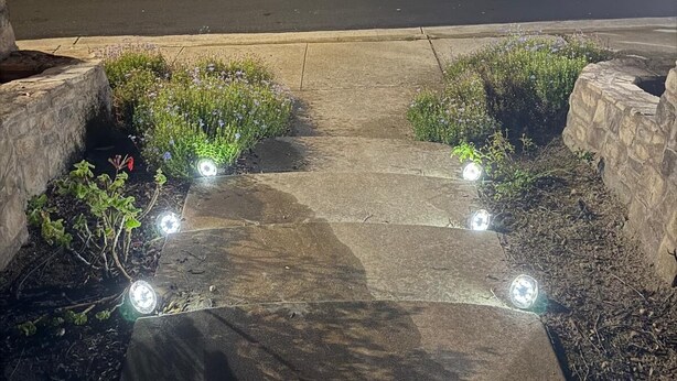 A residential driveway with a garage, a parked car, and a well-lit pathway leading to the house. - Dream house (Salinas)