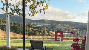 A patio with a bench, a stone pathway, and a view of a fenced area with a red structure. - Dream house (Salinas)