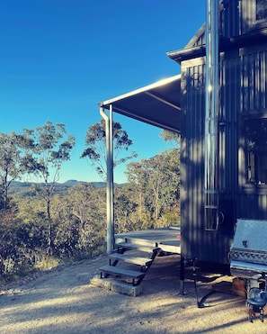 A modern building with a covered outdoor area, a metal structure, and a view of the surrounding landscape. - SummerHill tiny home romantic escape (Bucketty)