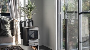 Ein gemütliches Zimmer mit Kamin, einem Fenster mit Ausblick, einer Pflanze und einem Tisch mit einer Auflage.