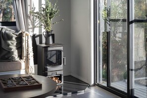 Una habitación acogedora con chimenea, ventana con vistas, una planta y una mesa con una bandeja de objetos.