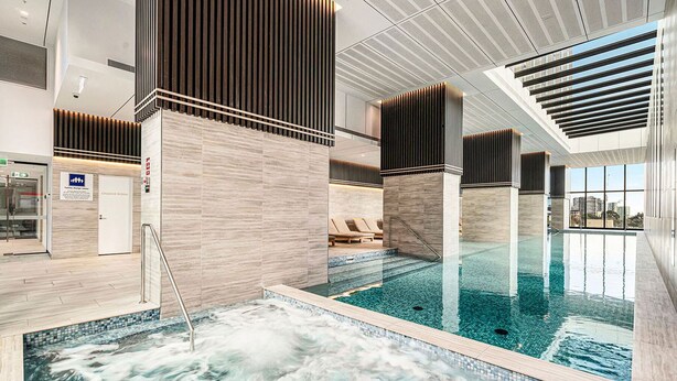 Piscina interna moderna con area idromassaggio, sedie a sdraio e spogliatoio.